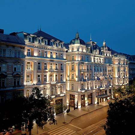 Corinthia Budapest Exterior photo The photo shows a beautifully illuminated historic building at night. The architecture features elegant details, including ornamental facades and a prominent roof structure, typical of classic European design. The building is lit up, highlighting its